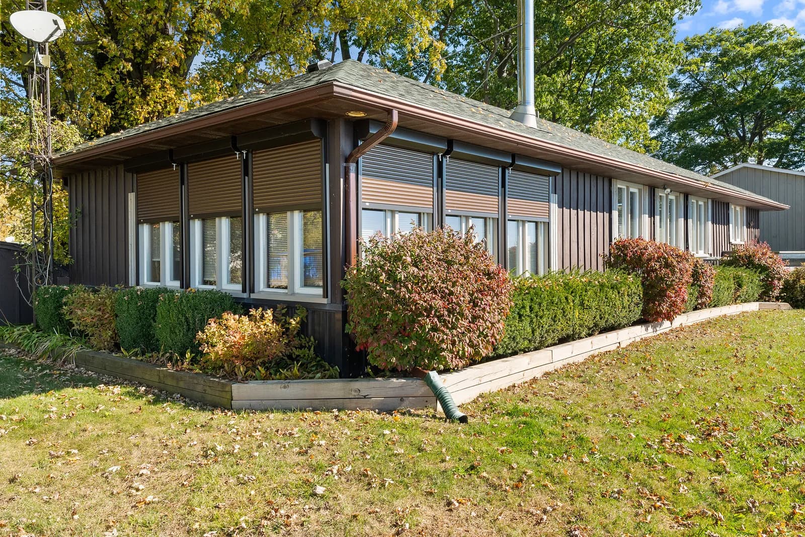 Brown bungalow with multiple aluminum roll shutters deployed across the side