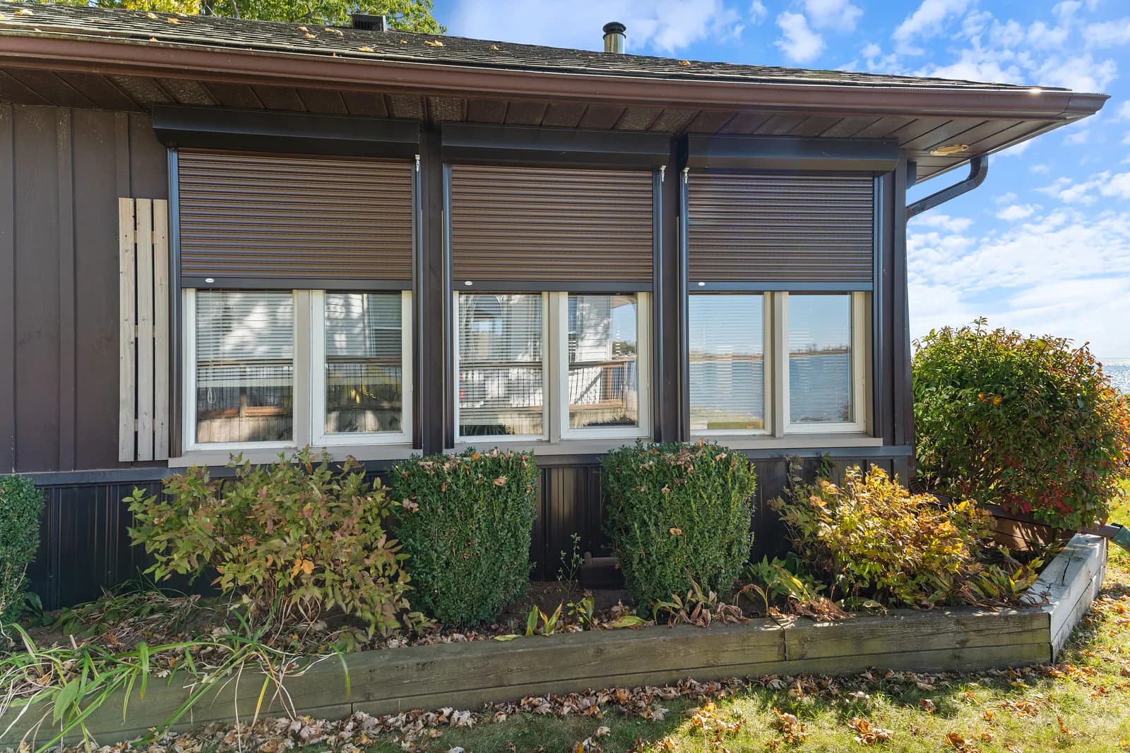 Ontario cottage with brown aluminum roll shutters deployed on the lakeside