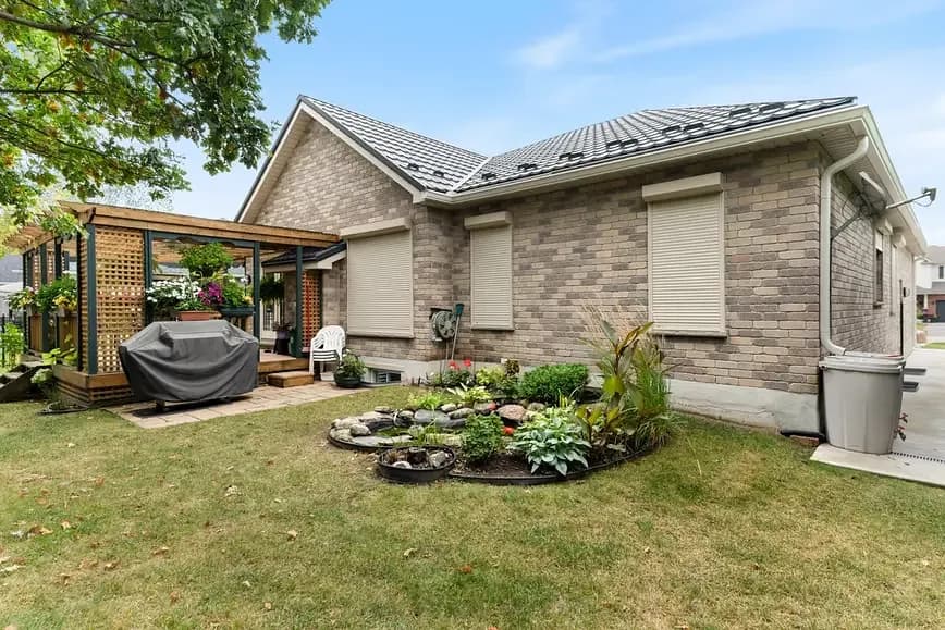 Light-brick Ontario home with multiple cream aluminum roll shutters deployed